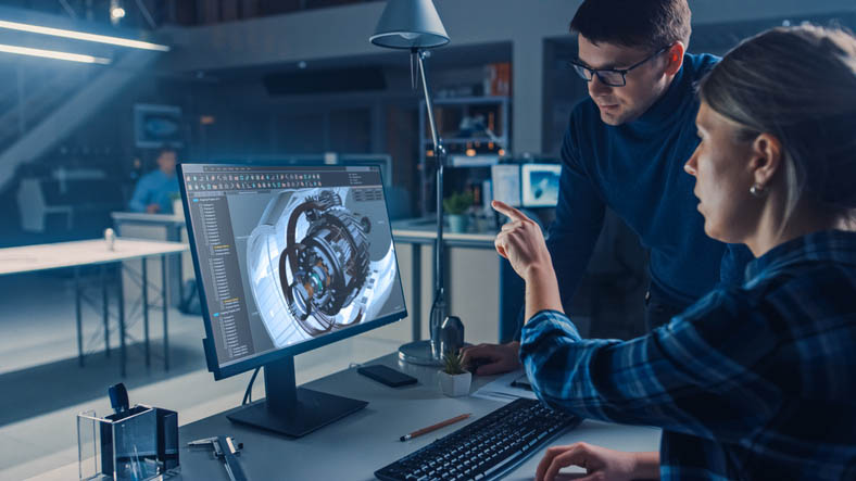 Two engineers view CNC design on computer monitor