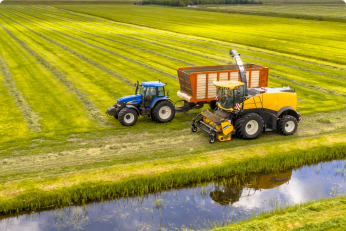 Tractors on freshly mowed green agricultural grass